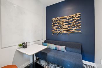 A blue couch with a white table and a wall art.